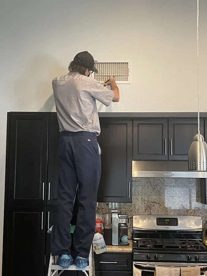 Technician inspecting an air vent during HVAC service in O'Hara